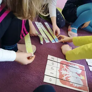 Dzieci oglądają książeczkę przy stoliku podczas zajęć
