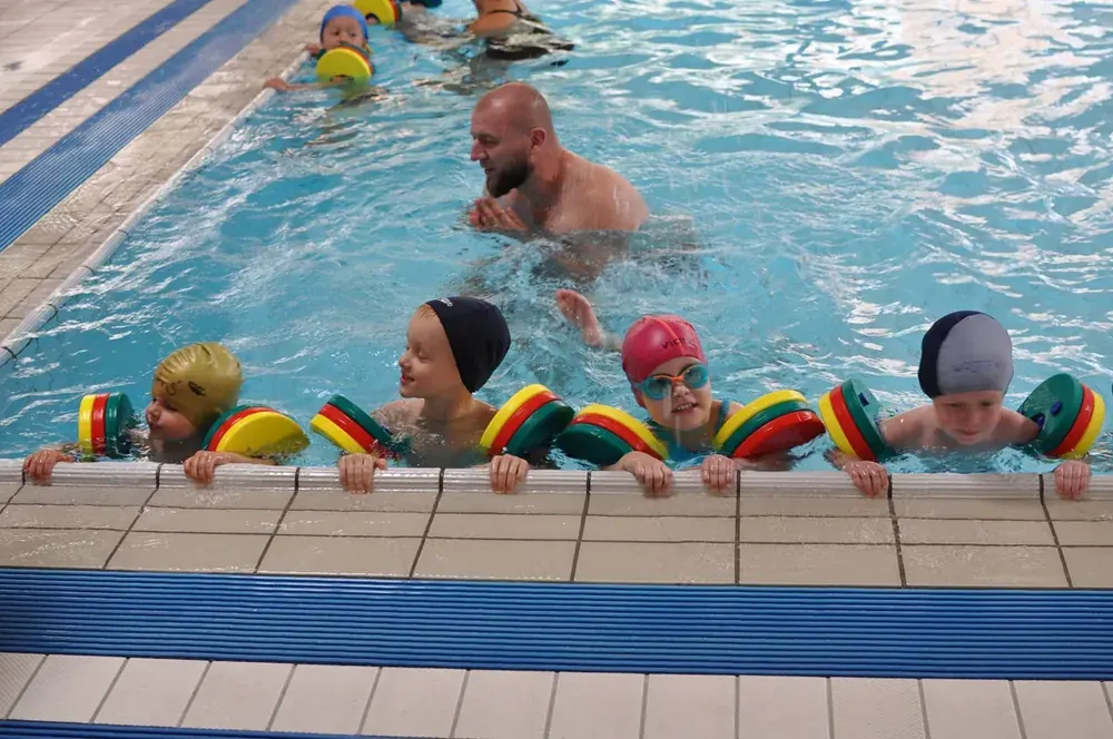 Dzieci podczas nauki pływania na basenie z instruktorem