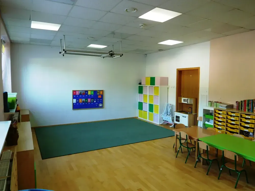 Przestronna, jasna sala przedszkolna z kolorowymi meblami