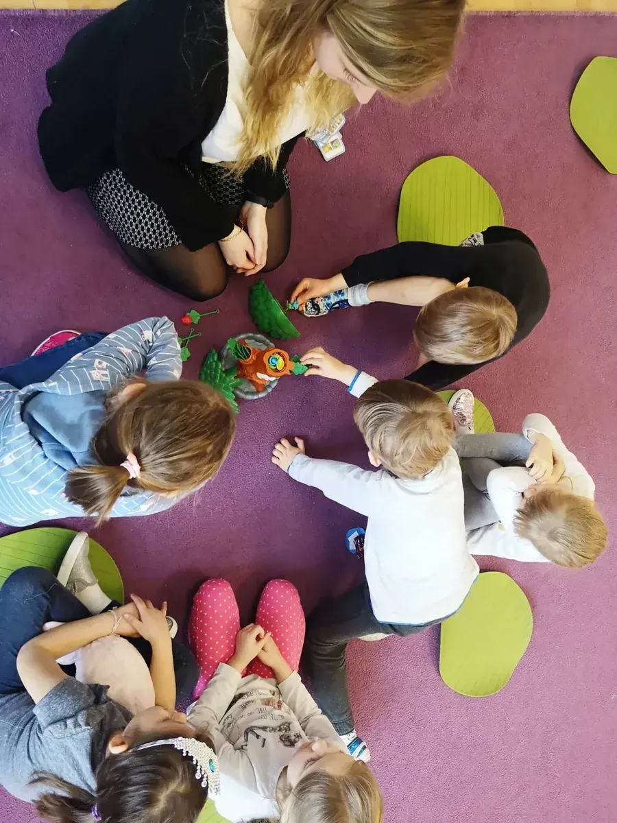 Nauczycielka podczas zajęć z grupą dzieci na dywanie